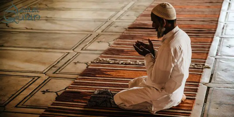 a person in white clothes and hat praying.